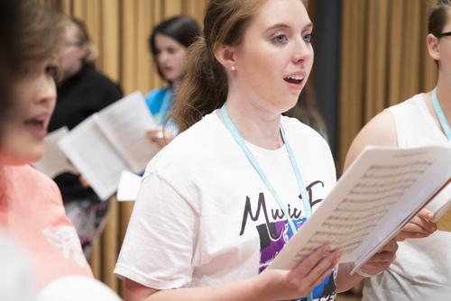 A vocal arts student sings from a page of sheet music.