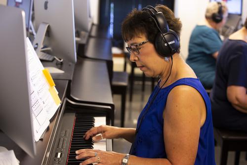A Music Academy member wearing a Yamaha headset practices playing the piano.