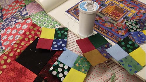 Image of quilting materials, including fabric, thread and a pattern book.