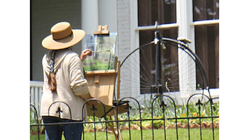 Image of Ellen Hahs Flentge painting on a canvas and easel outside.