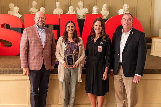 Professionals holding a plaque. 