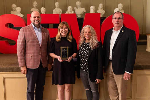 Professionals holding a plaque. 
