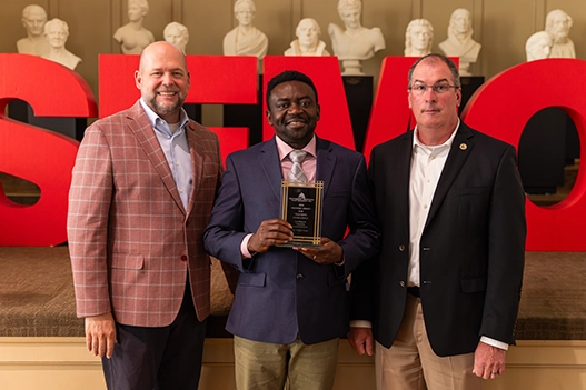 Professionals holding a plaque. 
