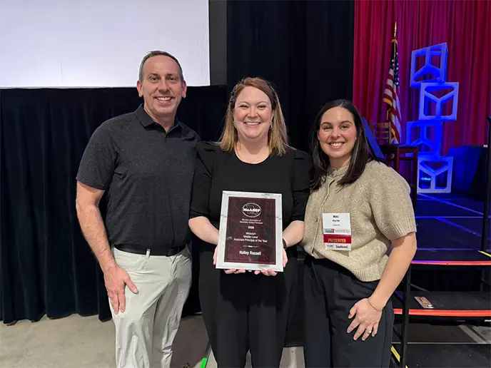 A photo of Halley Russell holding an award with educators from Cape Central School District.