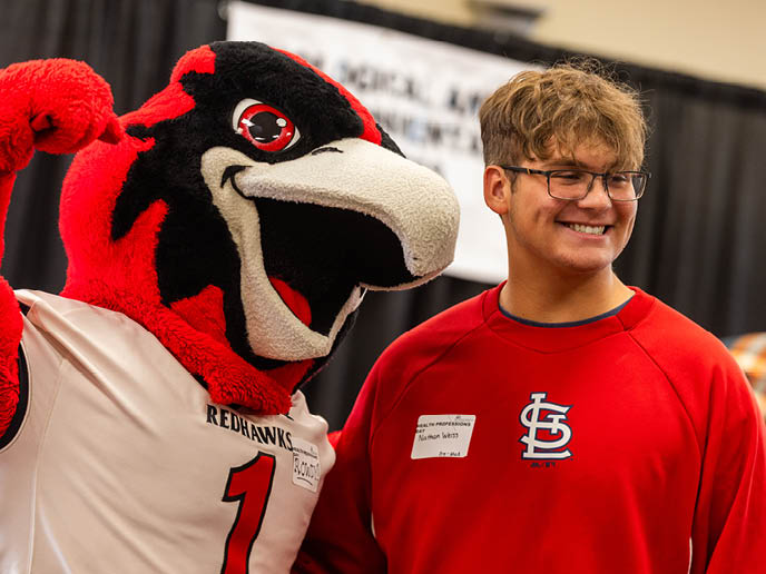 A prospective student poses for a picture with Rowdy.