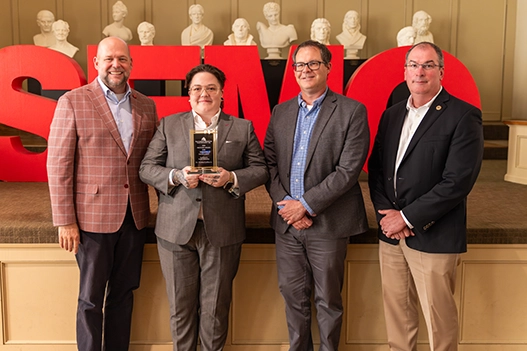 Professionals holding a plaque. 