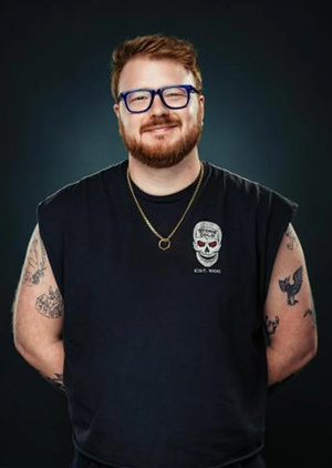 A young man poses against a black background.
