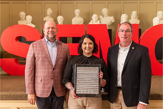 Professionals holding a plaque. 
