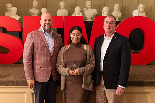 Professionals holding a plaque. 