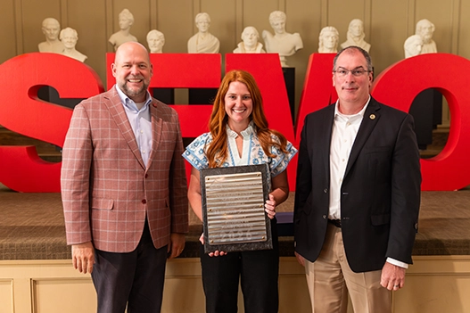 Professionals holding a plaque. 