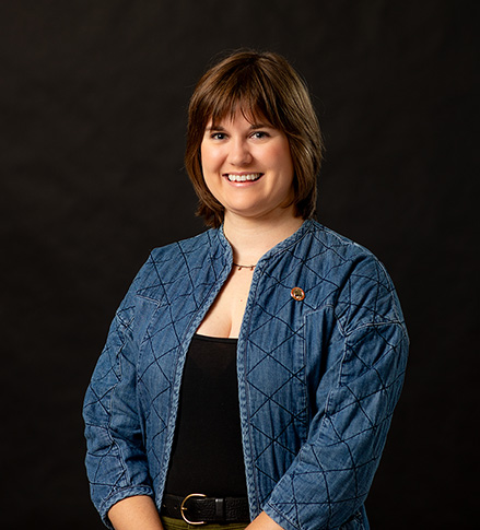 Professional portrait of Tara Meyer, SEMO alum, standing in front of a black background.