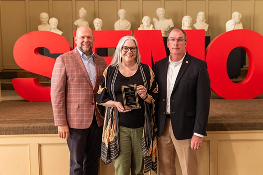 Professionals holding a plaque. 