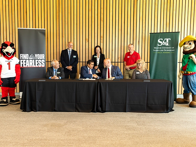 A group of professionals shake hands after signing an agreement.