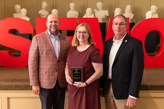 Professionals holding a plaque. 
