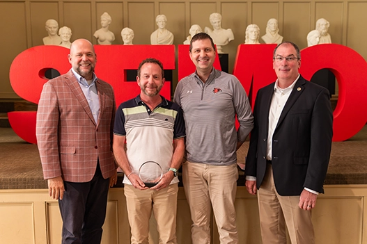 Professionals holding a plaque. 