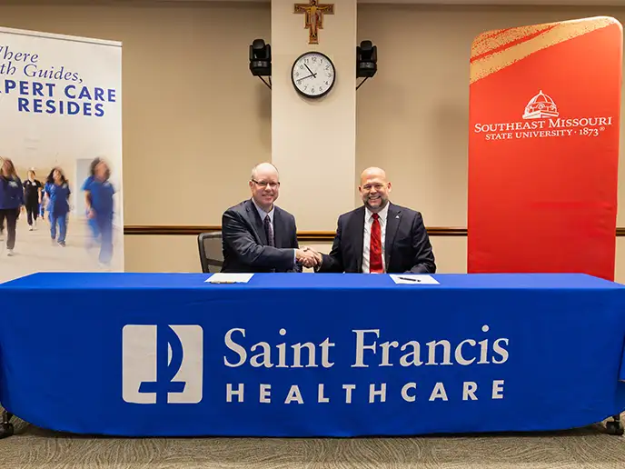 SEMO President Dr. Brad Hodson and Saint Francis Healthcare System President and CEO Justin Davison smile and shake hands.