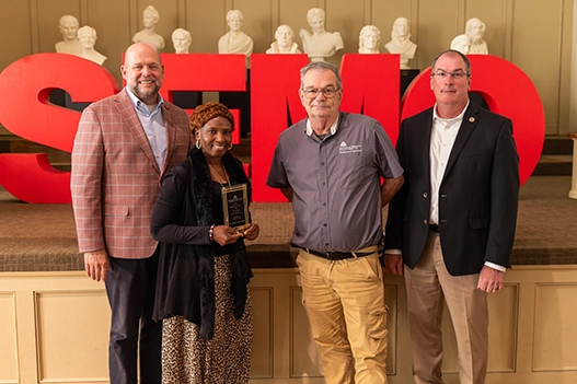 Professionals holding a plaque. 