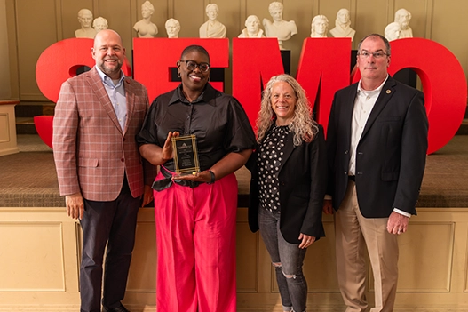 Professionals holding a plaque. 