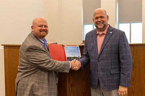 A photo of SEMO President Dr. Brad Hodson presenting a Top 5 Small College Town in America award at the Cape Girardeau City Council meeting.