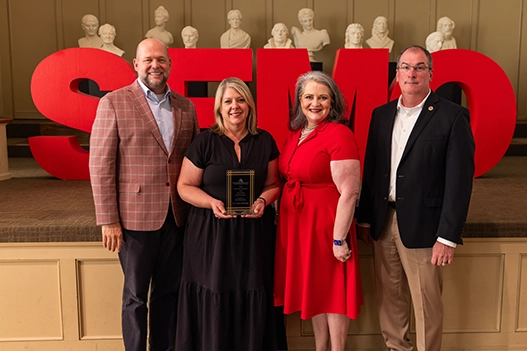 Professionals holding a plaque. 