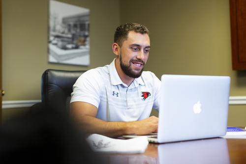 A SEMO Online student works on their laptop at a table.