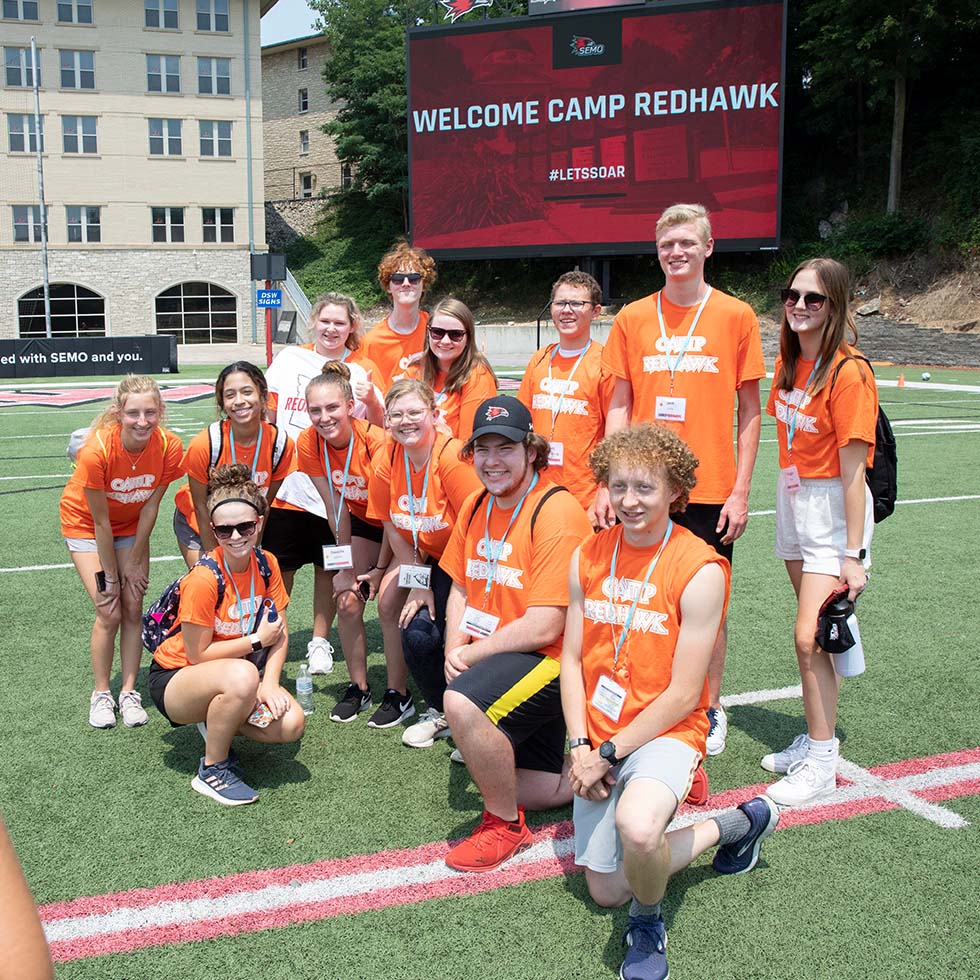 Camp Redhawk group all smiling for a photo on the football field