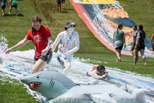 Three students going down a slip-n-slide.