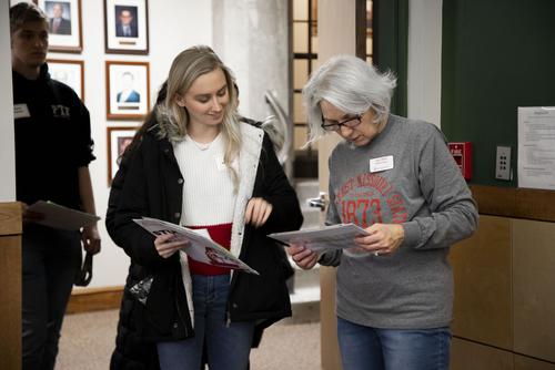A staff member looks at a chart to help direct a student to an academic advisor.