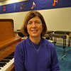 Image of Carol McDowell sitting at a piano bench.