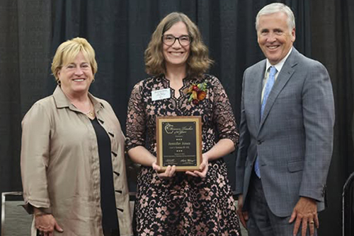 greg kester posing with a plaque and two other individuals
