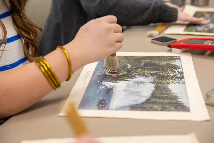 A student uses a small brush to preserve a historic painting from the Cape Girardeau Region. 