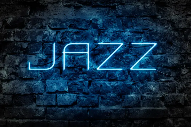 Neon blue sign that reads "jazz," on a brick wall