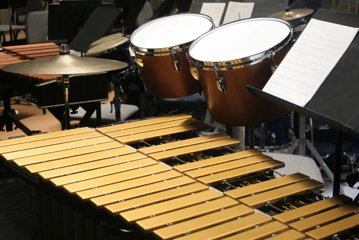 Percussion ensemble in a band room with stands and sheet music