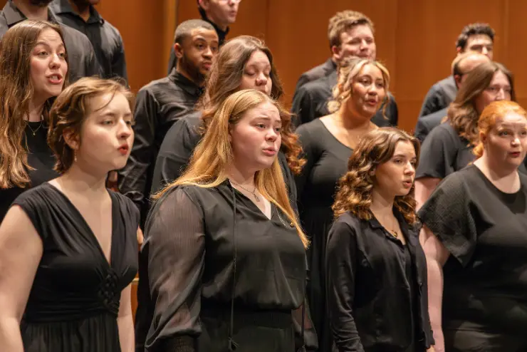 Chamber & University Choirs dressed in all black perform a song