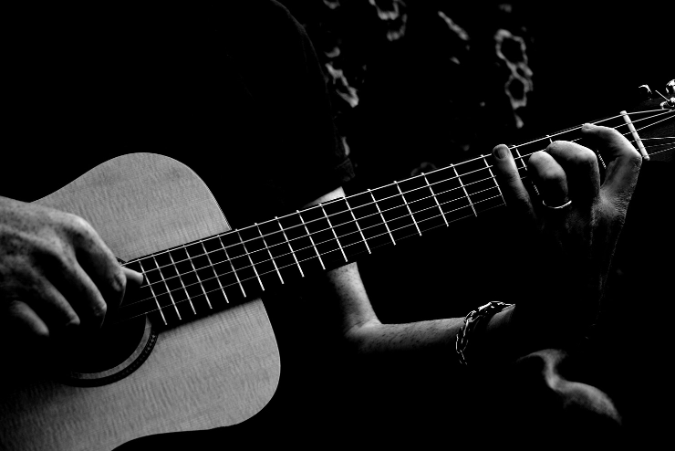 Grayscale close up of someone strumming a guitar