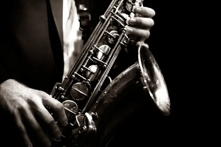 A black and white close up of a saxophone being held by a person in a suit