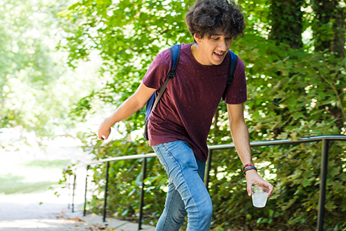A student reaching the top of Cardiac Hill with a water in hand