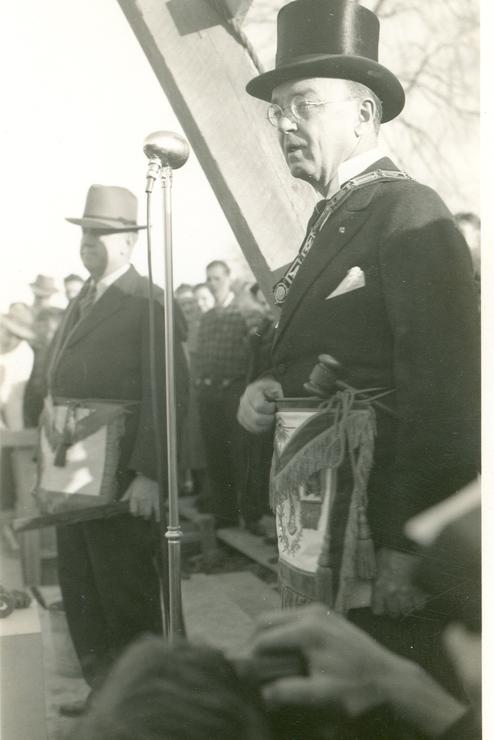 Man in a top hat speaking into a microphone at Cheney's opening ceremony.
