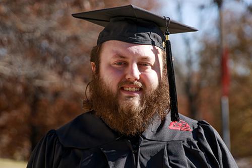 Graduate Andrew Last smiles while wearing his cap and gown.