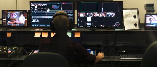 Mass Media student works in front of computer screens.