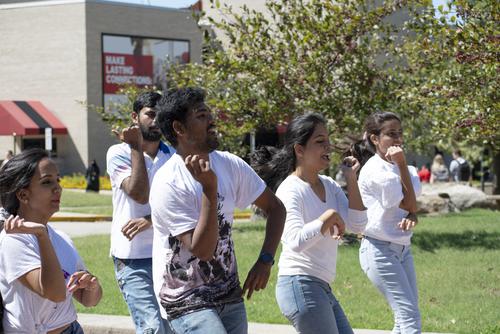 Three students dancing in the street to celebrate international week