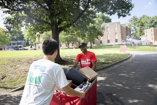 students moving items in a cart up a hill