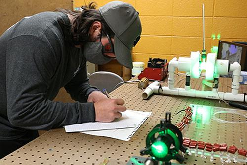 A student writes notes while conducting research in a laboratory