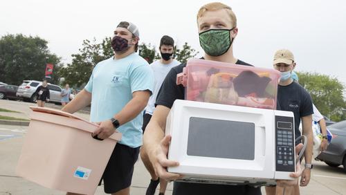 A student carrying a microwave during student move-in