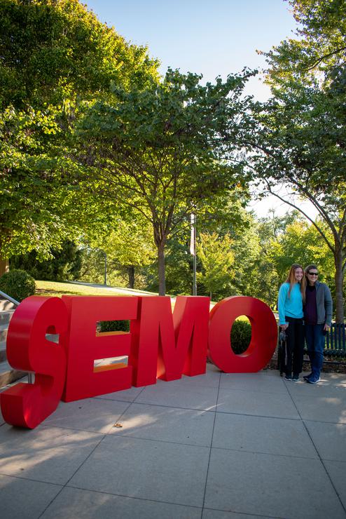 A parent and a student pose next to giant red letters that spell out SEMO