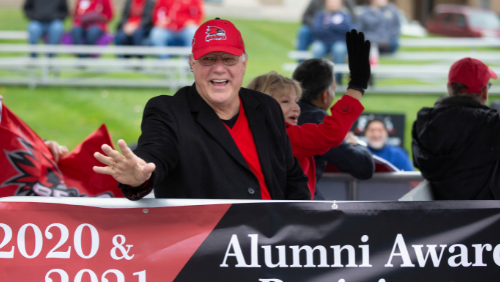 An Alumni Award Recipient waves to the parade crowd.