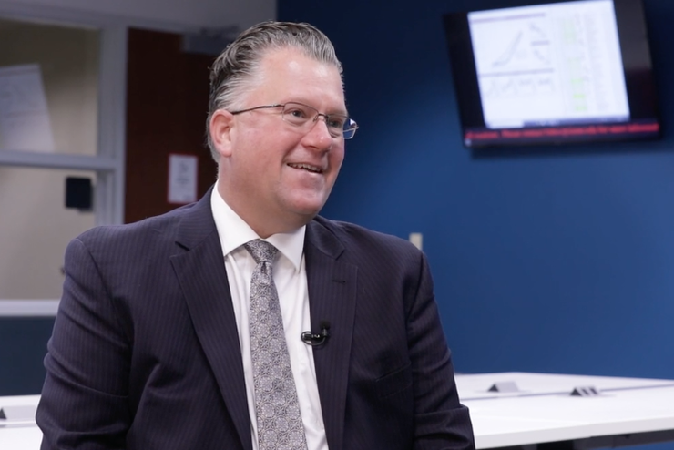 Scott Giles smiles while sitting in a classroom.