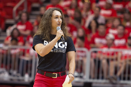 Peyton standing holding a microphone speaking to a new class of students