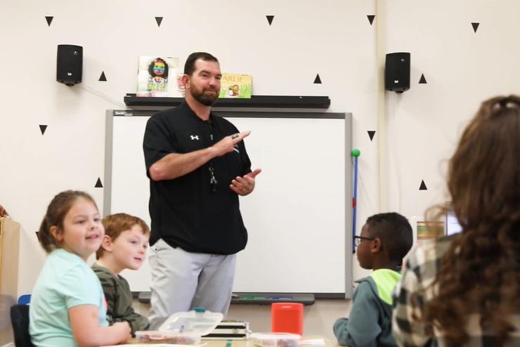 Coach Tuke stands before a kindergarten class.
