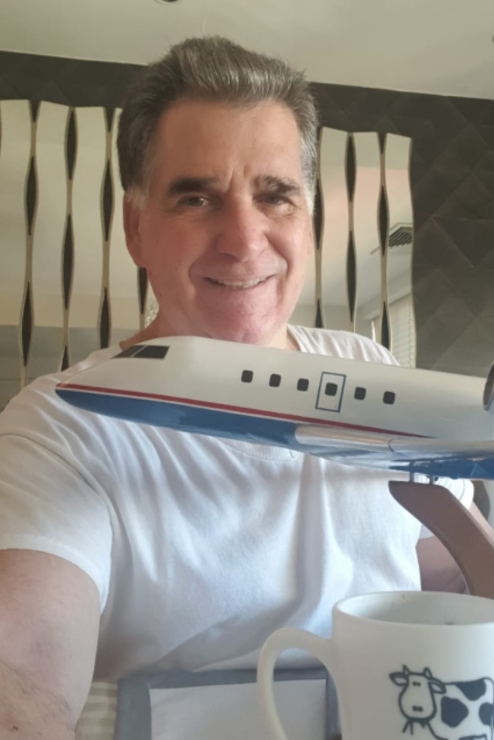 Alejandro Torres smiles for a photo with a model plane.